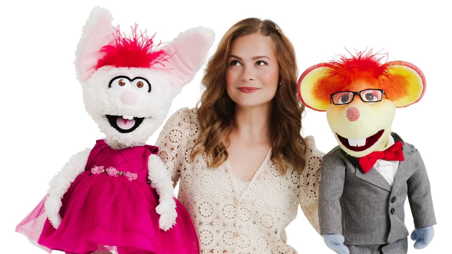 Darci Lynne in a cream lace top between her puppets Petunia, a white rabbit in a pink dress, and Oscar, a mouse in glasses and a gray suit