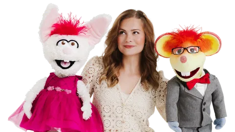 Darci Lynne in a cream lace top between her puppets Petunia, a white rabbit in a pink dress, and Oscar, a mouse in glasses and a gray suit